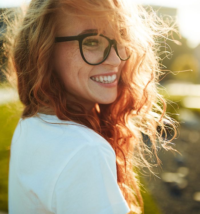 Portraits of a charming red-haired girl with a cute face. Girl posing for the camera in the city center. She has a wonderful mood and a lovely smile.